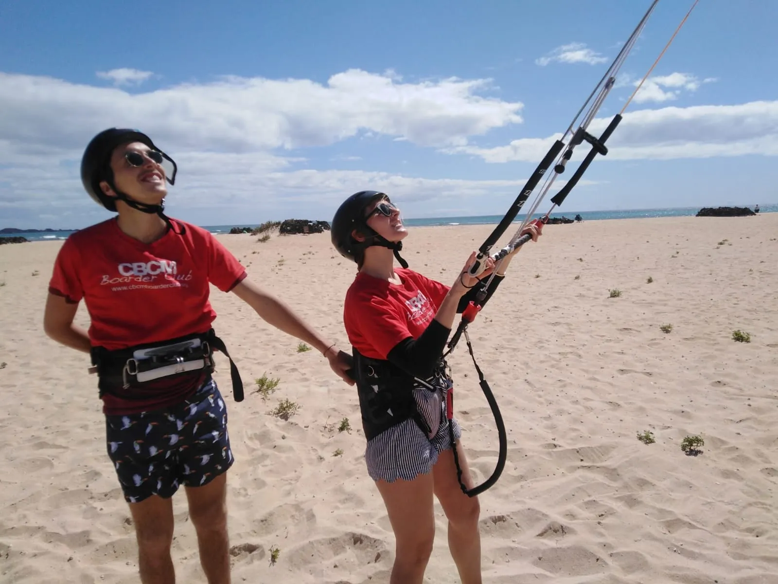 Monitor de CBCM enseñando a una alumna a manejar la barra de la cometa en la playa