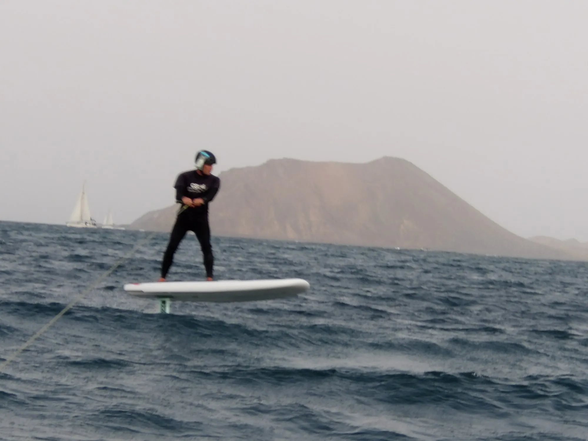 Rider sobre una tabla de foil con el volcán de Lobos al fondo