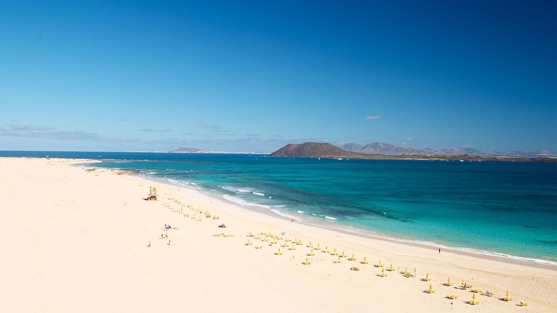 Vue aérienne de Grandes Playas, à Corralejo : sable blanc, eau turquoise et l'île de Lobos au fond