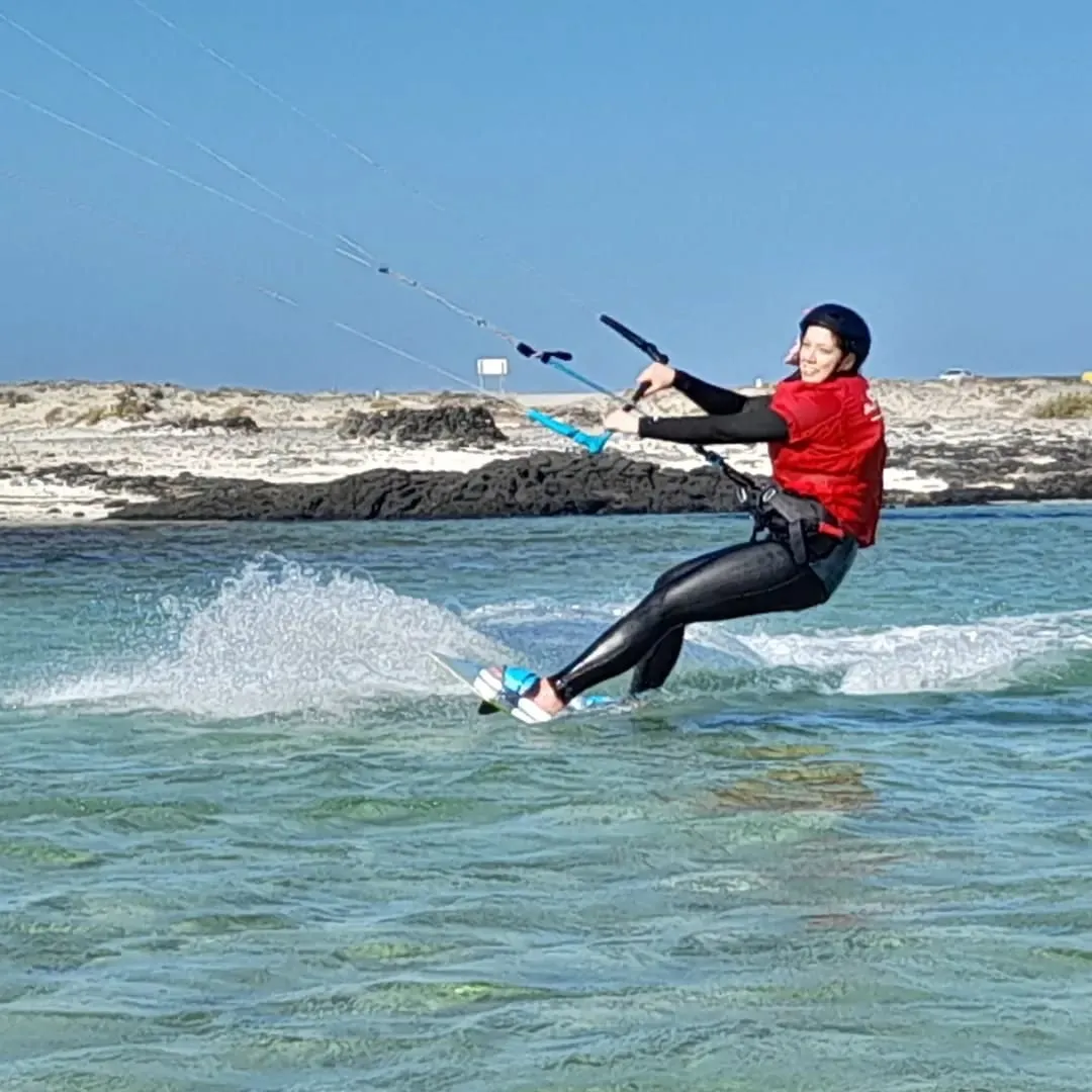 Alumna de kitesurf navegando en la laguna con licra roja de CBCM