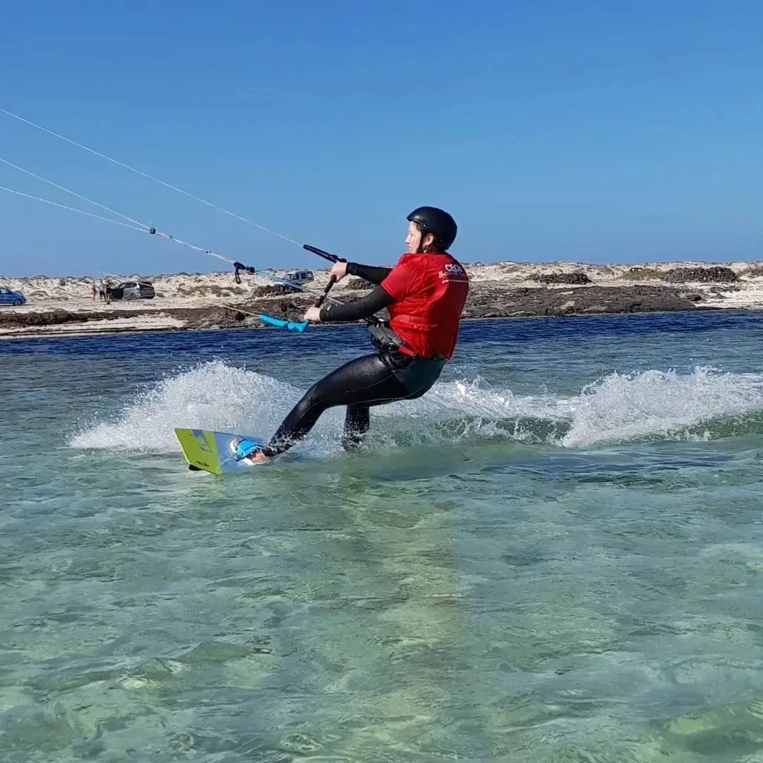 Alumno de kitesurf deslizándose sobre el agua transparente de la laguna