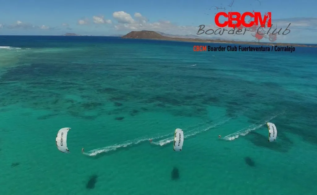 Cometas de kitesurf sobre agua turquesa con la isla de Lobos al fondo