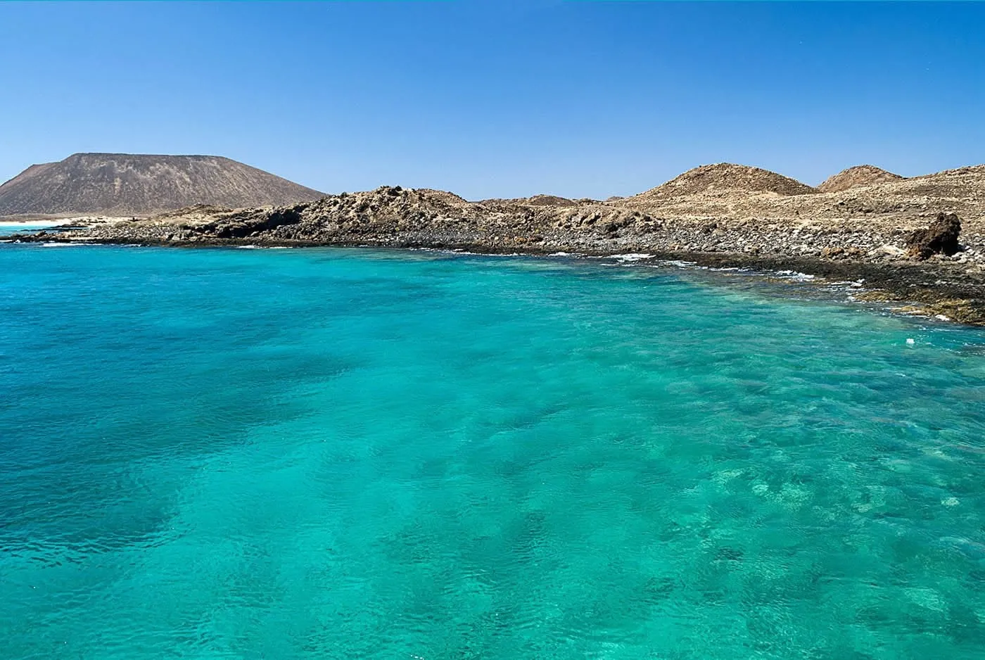 Agua turquesa en la costa de la isla de Lobos, con su volcán al fondo